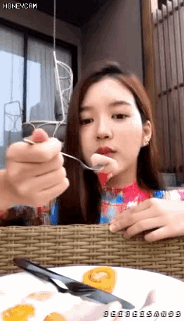 a woman is eating a piece of food with a spoon from a plate that says honeycam on the bottom