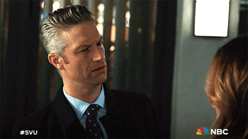 a man in a suit and tie is talking to a woman with a nbc logo behind him