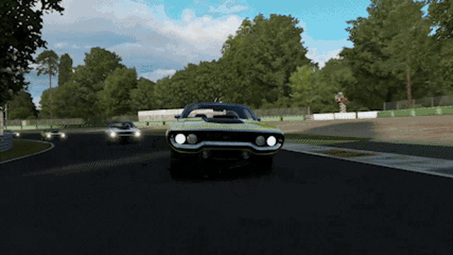 a yellow car is driving on a race track with other cars