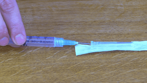 a person is holding a syringe which says single use on it