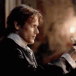 a man in a suit is holding a glass of wine in his hand .