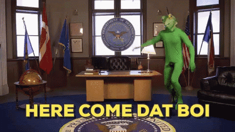 a man in a green suit is dancing in front of a desk with the words here come dat boi on it