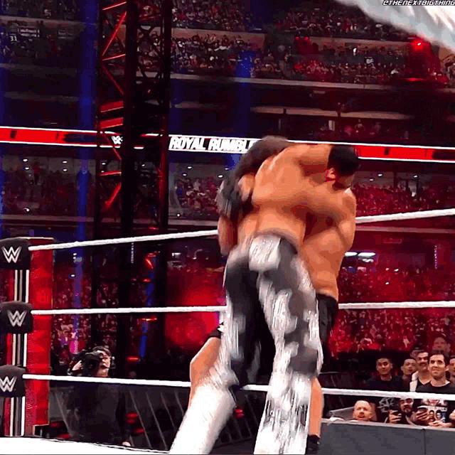 two wrestlers in a wrestling ring with the word royal rumble in the background