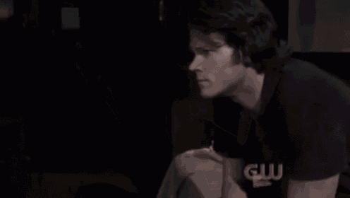 a man is sitting in a dark room holding a cell phone in his hand .