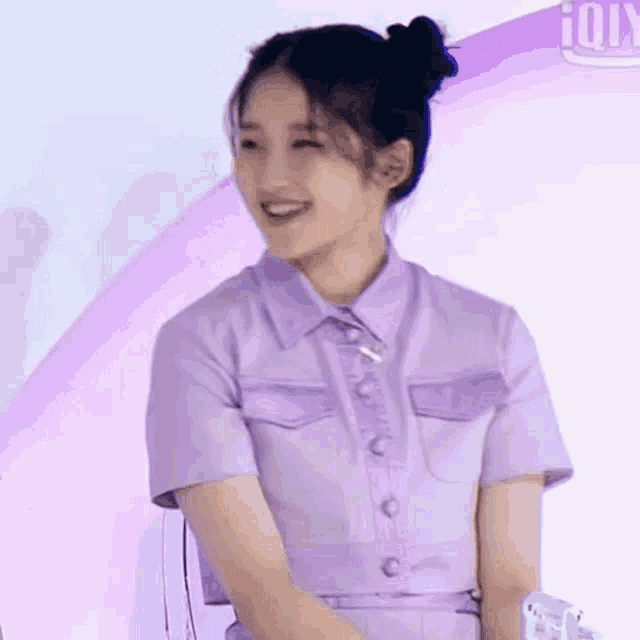 a woman in a purple shirt and pants is smiling and looking at the camera .