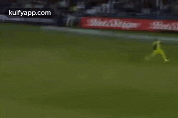 a cricket player is running on a field with a toyota ad in the background .