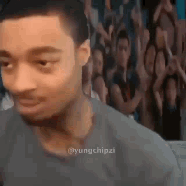 a man is making a funny face in front of a crowd .