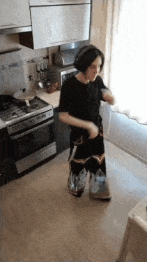 a person in a kitchen wearing headphones and a black shirt
