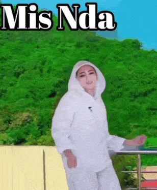 a woman in a white coat with a hood is dancing in front of a green forest with the words mis nda above her