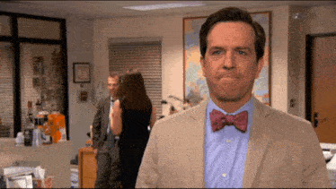 a man wearing a bow tie looks at the camera in an office