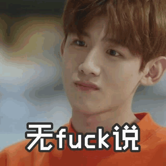 a young man in an orange shirt is making a funny face and saying `` fuck '' in chinese .