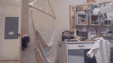 a room with a hammock hanging from the ceiling and a desk with pictures on it