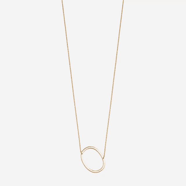 a gold necklace with a large oval pendant
