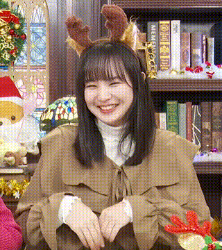 the girl is wearing a reindeer headband and smiling .