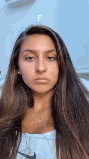a woman with long hair is wearing a white nike shirt and a necklace .