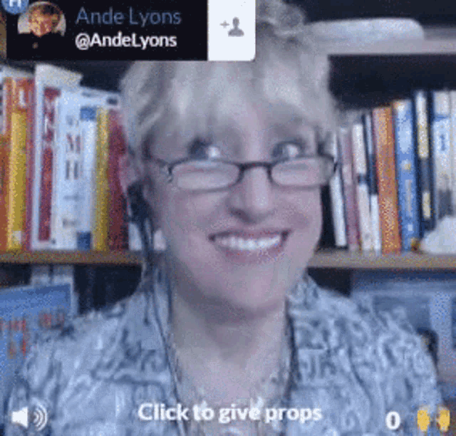 a woman wearing glasses is smiling in front of a bookshelf