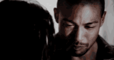 a black and white photo of a man and woman looking into each other 's eyes .
