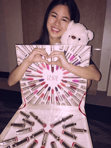 a woman is holding a box of pure color love lipstick