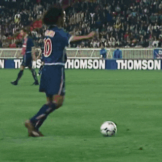a soccer player with the number 14 on his jersey stands on the field