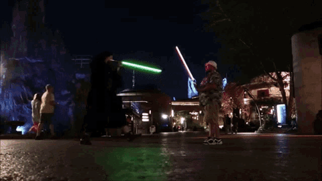 a man holding a green light saber stands next to another man in a white hat