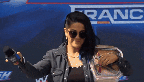 a woman wearing sunglasses holds a microphone in front of a sign that says ' ranch '