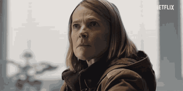 a woman in a brown jacket with the word netflix on the bottom right