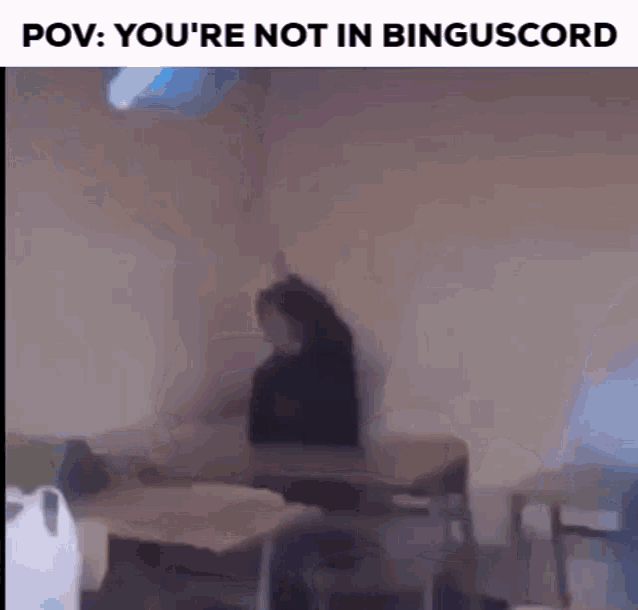 a blurry picture of a person sitting at a table in a room with a projector .