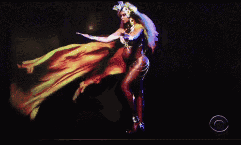 a pregnant woman is dancing in front of a cbs logo on a screen