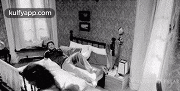 a black and white photo of two people laying on a bed .