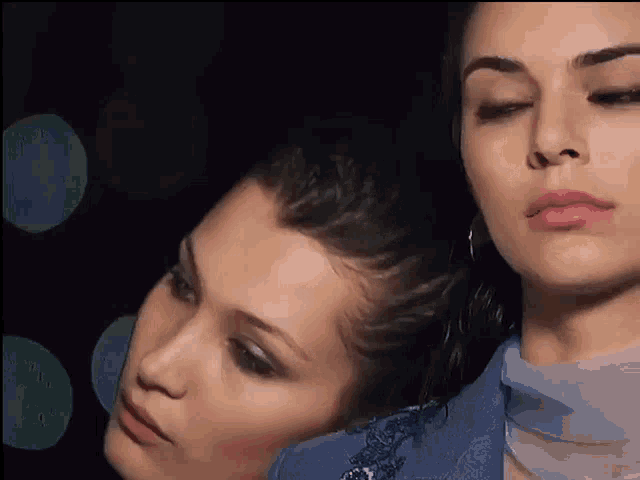 a close up of two women 's faces in a dark room .