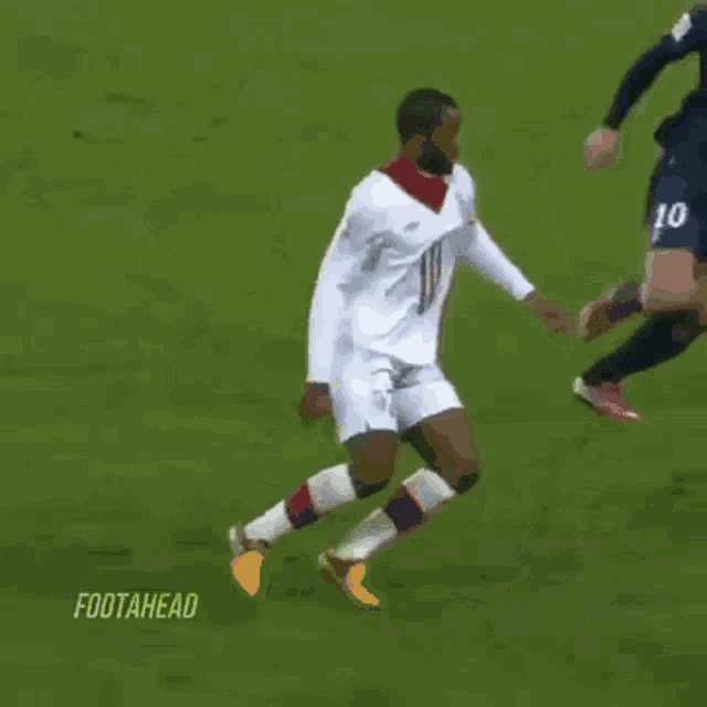 a soccer player wearing a fly emirates jersey kicking a soccer ball