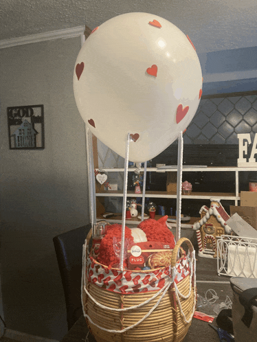 a hot air balloon with hearts on it is sitting on top of a basket