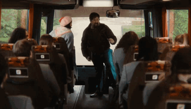 a group of people sitting on a bus with a man standing in the middle