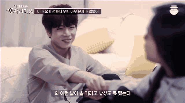 a man and a woman are sitting on a couch and the man is smiling and the woman is holding his hand