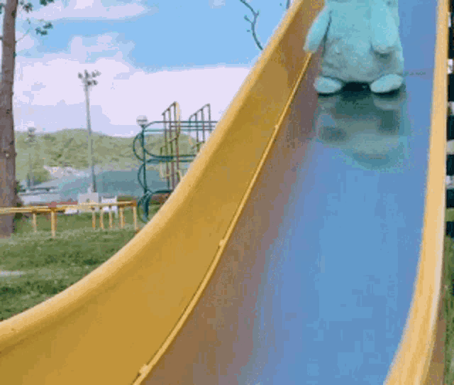 a stuffed animal is sliding down a slide in a park