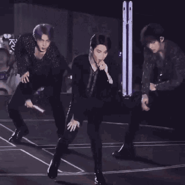 a group of men are dancing on a stage with a crowd watching .