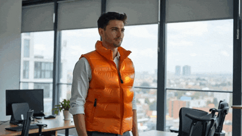 a man in an orange vest stands in front of a large window