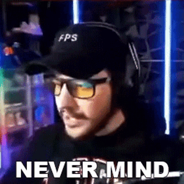 a man wearing a hat and glasses is sitting in front of a computer with the words `` never mind '' .