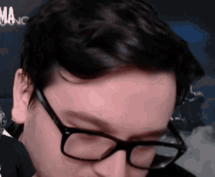 a man wearing glasses and a black shirt is looking down .
