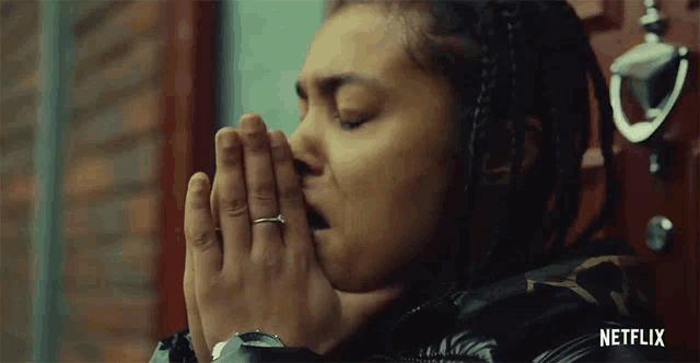 a woman with a ring on her finger is praying in front of a door that says netflix