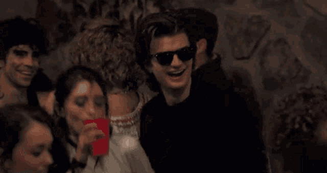 a man wearing sunglasses is dancing with a woman in a club .