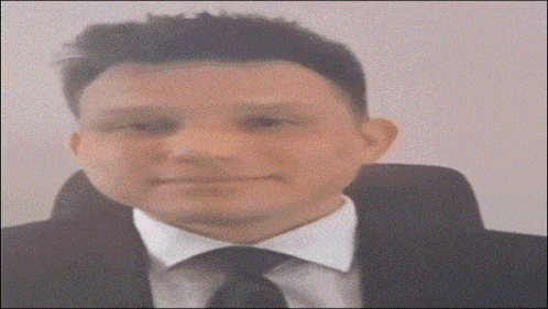 a man in a suit and tie is smiling and looking at the camera