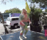 a woman is dancing on a table in front of a white van .