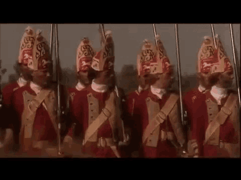 a group of soldiers wearing red uniforms and hats are marching in a line .