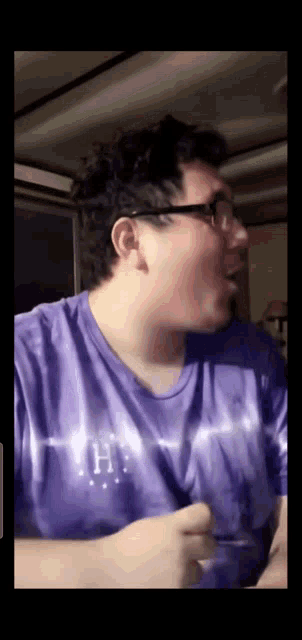 a man wearing a purple shirt with the letter h on the front