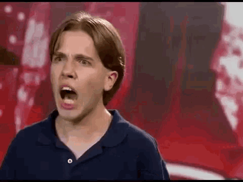 a young man in a blue polo shirt is making a funny face with his mouth open .
