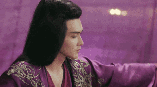 a man with long black hair wearing a purple jacket