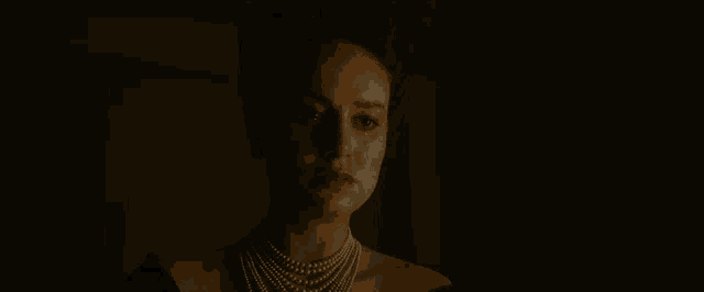 a woman wearing a pearl necklace and a black dress