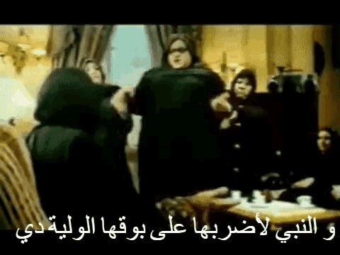 a group of people are standing in a room with arabic writing on it