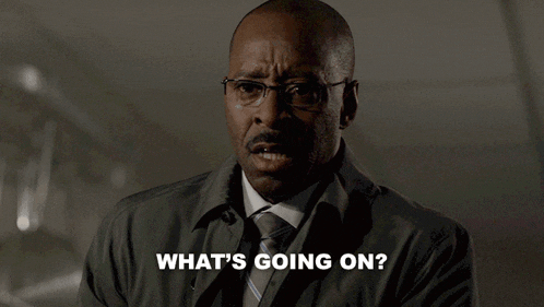 a man wearing glasses and a trench coat says what 's going on